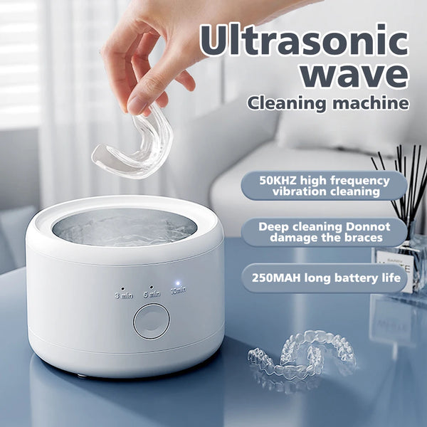 Ultrasonic wave cleaning machine with a hand placing a clear dental device into it, set against a blurred indoor background.